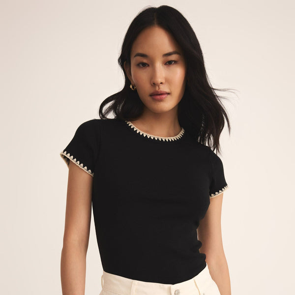 front view of the model wearing the cassis rib tee. shows the crew neckline. also shows the fitted style, the black color, the cream stitching on neckline and sleeves.