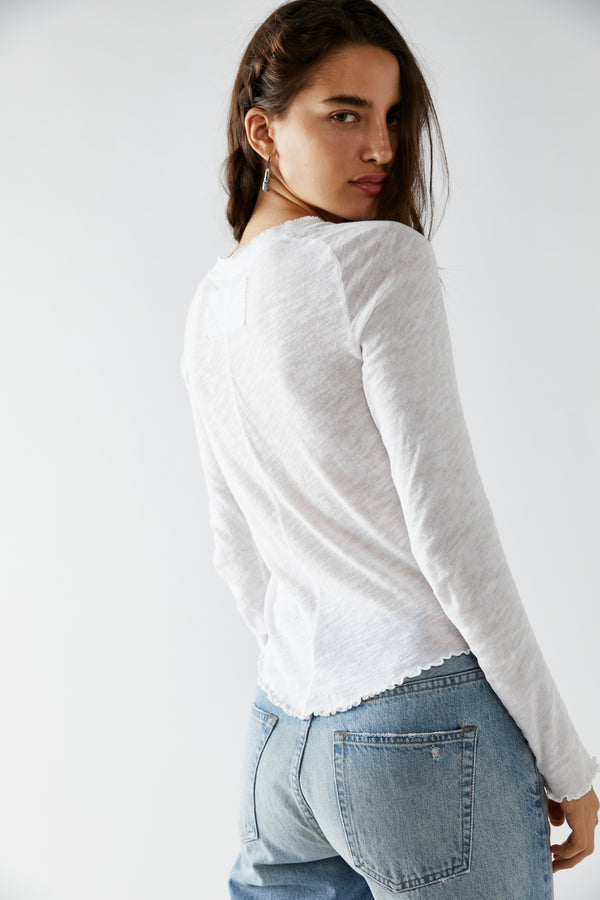 back/side view of model wearing the be my baby long sleeve in ivory. shows the rounded Botton hem. also shows the lettuce trim hemlines and the defined seaming down the middle.
