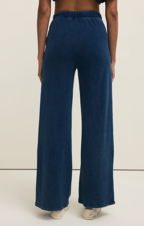 Person wearing blue wide-leg jeans on a beige background