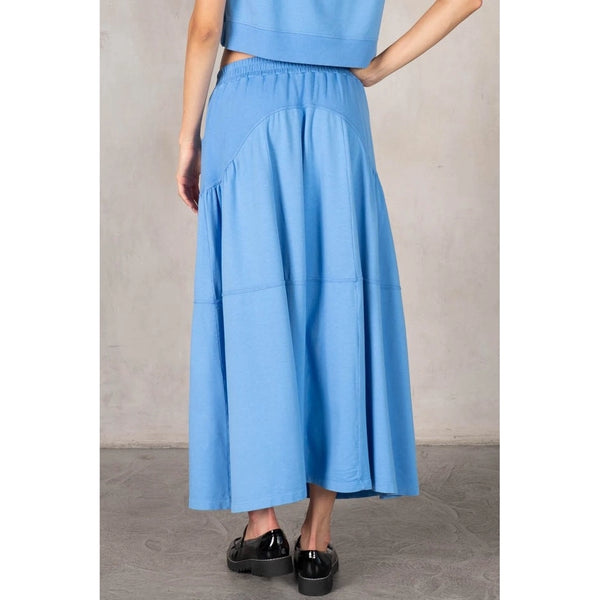 Person wearing a blue skirt with a plain background