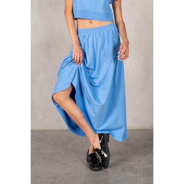Person wearing a blue outfit with a skirt and black shoes on a plain background
