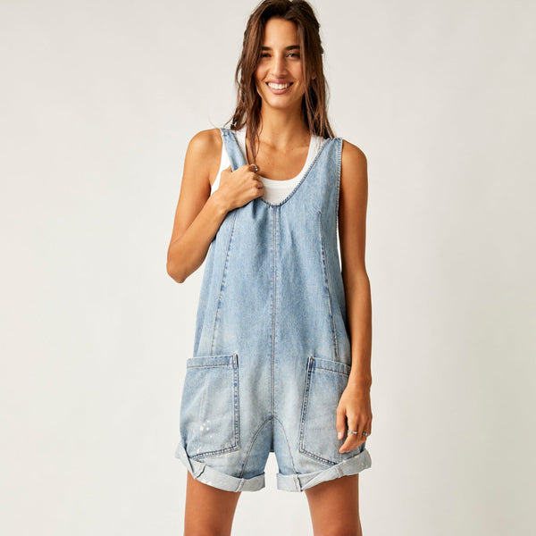 front view of model wearing the high roller shortall in bright eyes. shows the low neckline. also shows the defined seams, the two front patch pockets and the cuffed hem of the shorts. 
