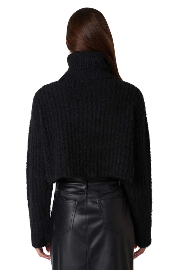 Back view of model wearing sweater. Shows the fun ribbed detailing, the soft fuzzy knit, the crop length of the sweater and the color of the sweater is black. 