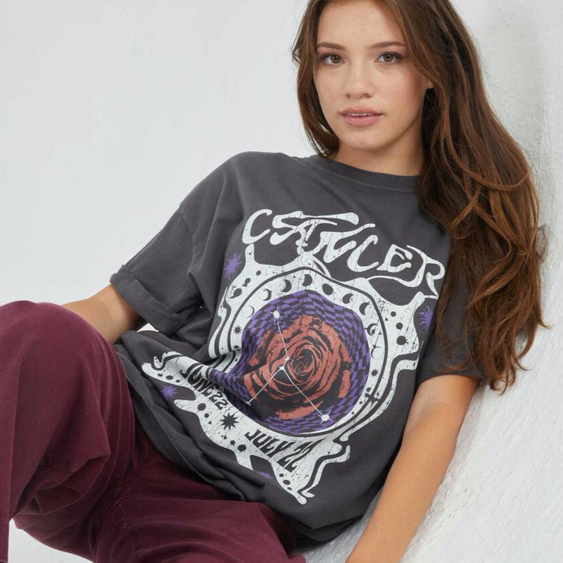 Front view of model wearing tee. Shows the crew neckline. Also shows the cuff sleeves, distressing on neckline and the cancer zodiac graphic. 