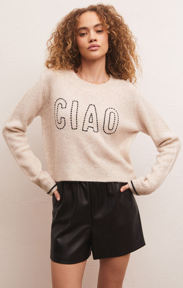 another front view of model in sweater. shows the crew neckline, contrast stripe detail on sleeve and chain stitch lettering "ciao"