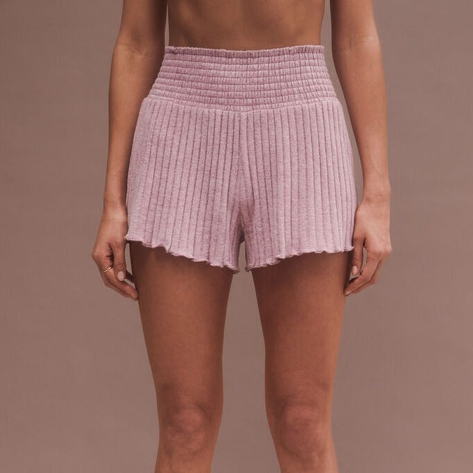 front view of model in shorts. shows the ribbed fabrication,  high waist, smocked waistband and lettuce edge hem,.