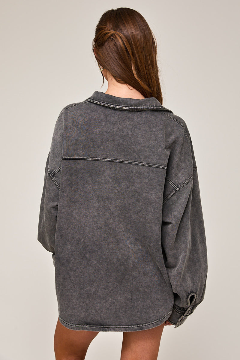 back view of the model wearing the vivian washed oversized long sleeve shirt. shows the curved hem. also shows the dropped shoulders, the washed look, the collar and the oversized fit. 