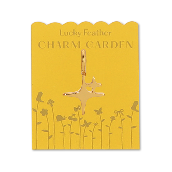Front view of spark charm on the yellow packaging. Shows the gold flowers and wording LUCKY FEATHER CHARM GARDEN. Also shows the gold spark charm. Size is little bit smaller than a dime. 