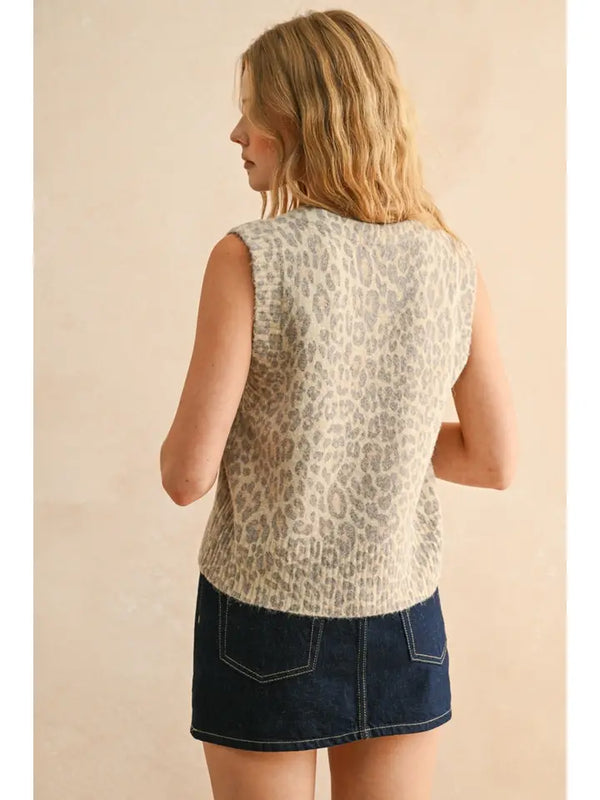 Woman wearing a sleeveless leopard print top and denim skirt on a beige background