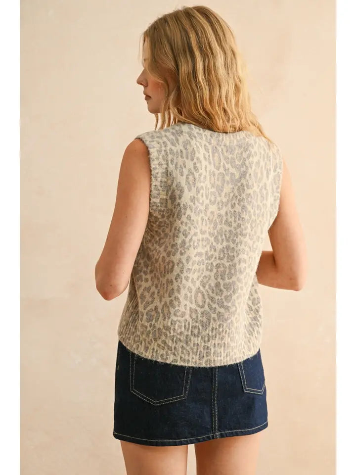 Woman wearing a sleeveless leopard print top and denim skirt on a beige background