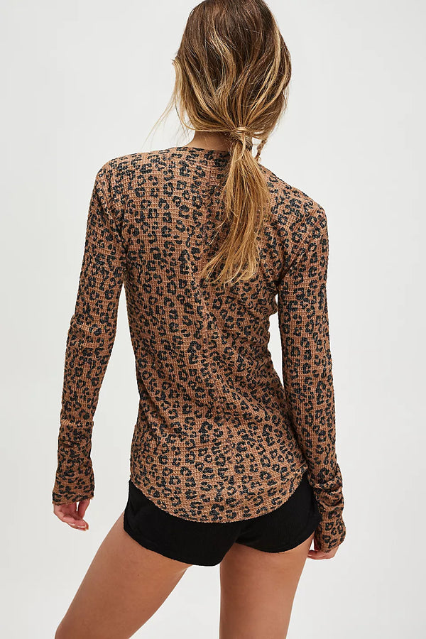 Person wearing a leopard print long-sleeve top and black shorts on a white background