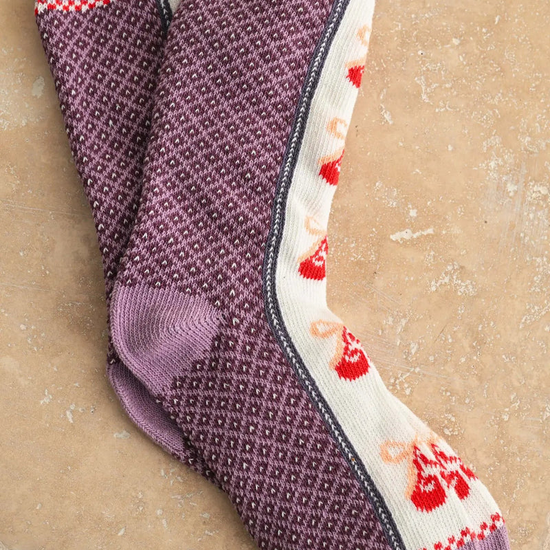 Pair of purple textured socks with red accents on a beige background