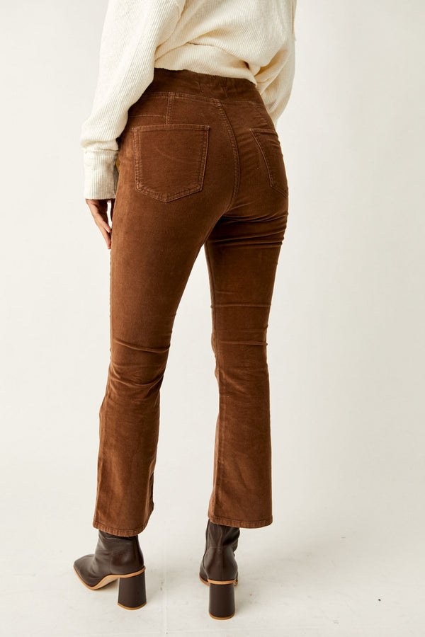 Back view of model wearing pants. Shows the back pockets. Also shows the defined seaming right above the back pockets, the cropped flare bottoms, the mid rise and the beautiful chocolate color. 
