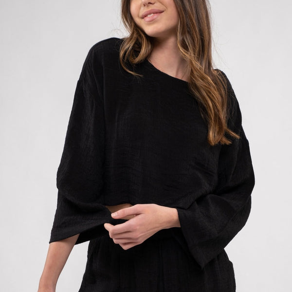 front view of the model wearing the Vivian cropped top in black. Shows the wide sleeves. also shows the boxy, relaxed fit, and the U neckline. 