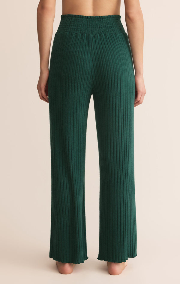 Green pleated pants worn by a person on a beige background