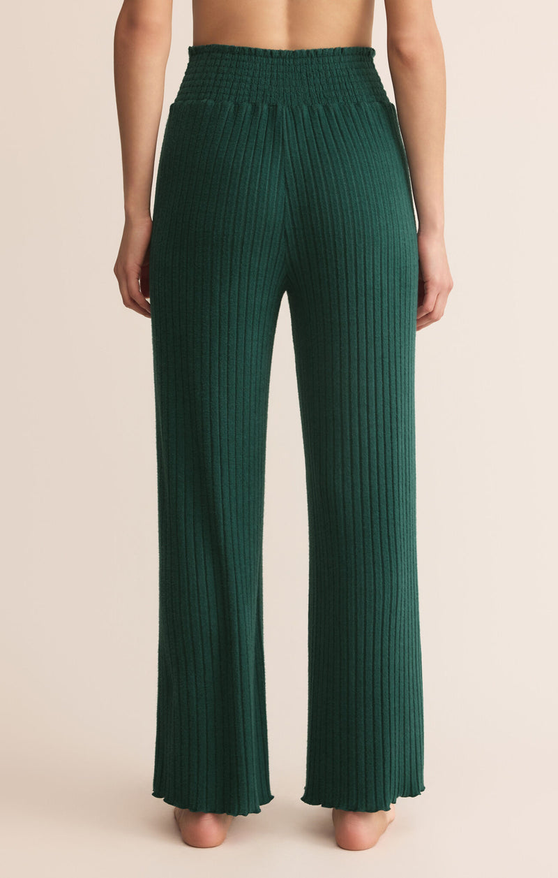 Green pleated pants worn by a person on a beige background