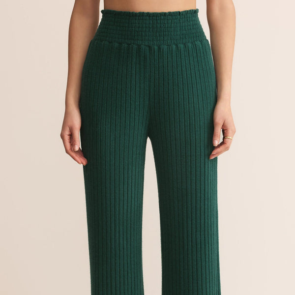 Green ribbed pants worn by a person on a beige background