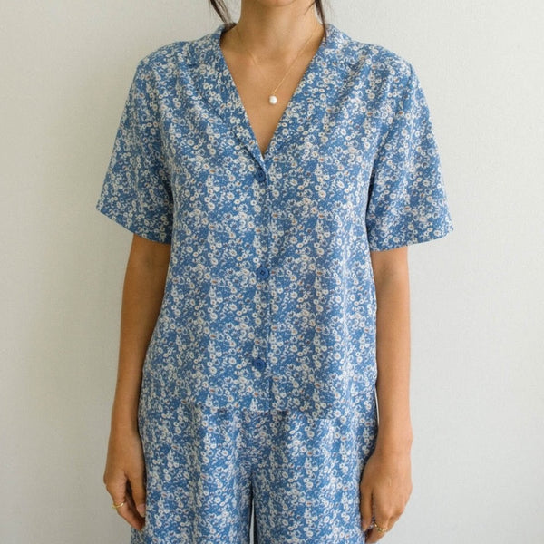 Front view of the model in the Selena Floral button down. Shows the functional buttons. Also shows the collar and the short sleeves. Shows the beautiful floral print. 