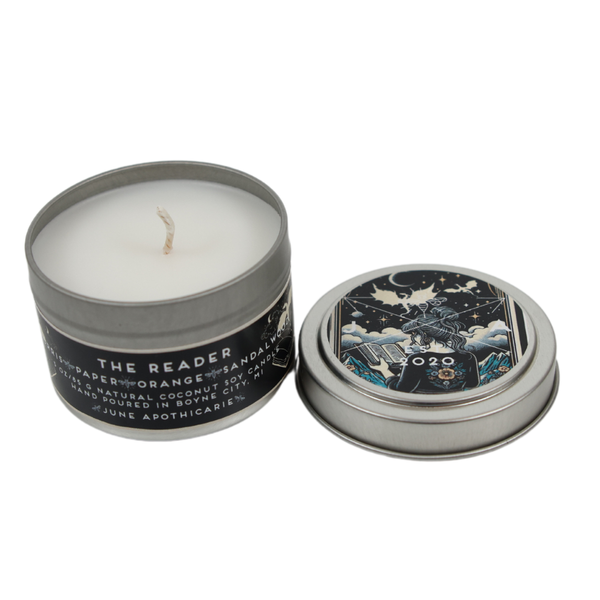 Candle in a tin with decorative lid on a white background