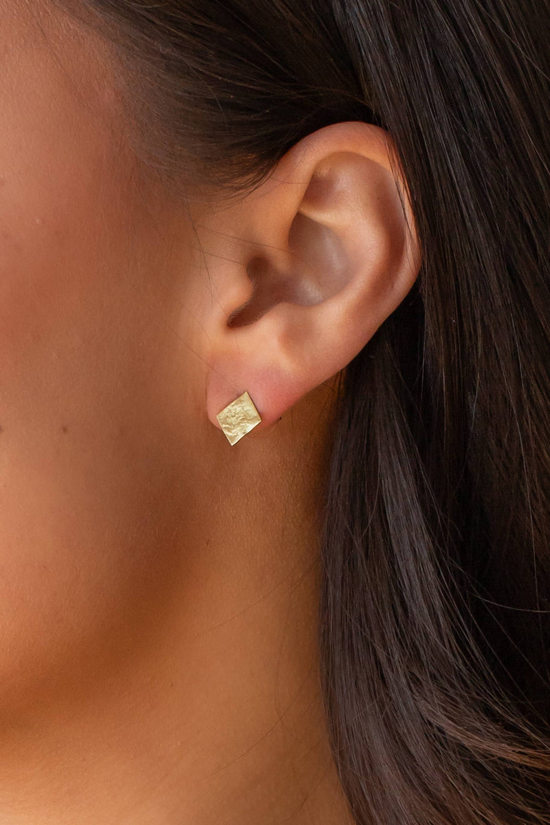 view of the model wearing diamond shaped gold textured earring.