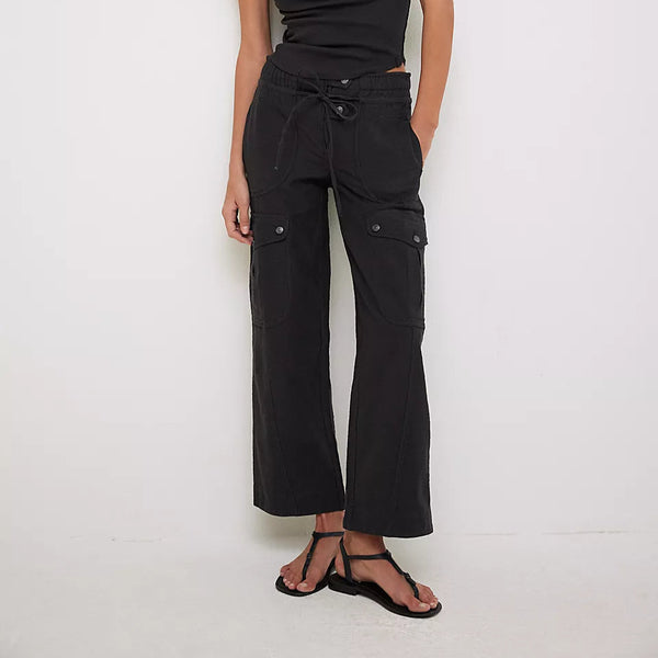 front view of the model wearing the park ave pant. shows the multi pockets. also shows the button & tie closure, the black color and the mid rise. 