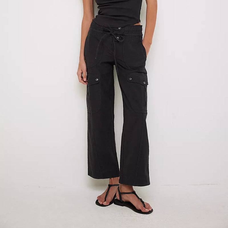 front view of the model wearing the park ave pant. shows the multi pockets. also shows the button & tie closure, the black color and the mid rise. 