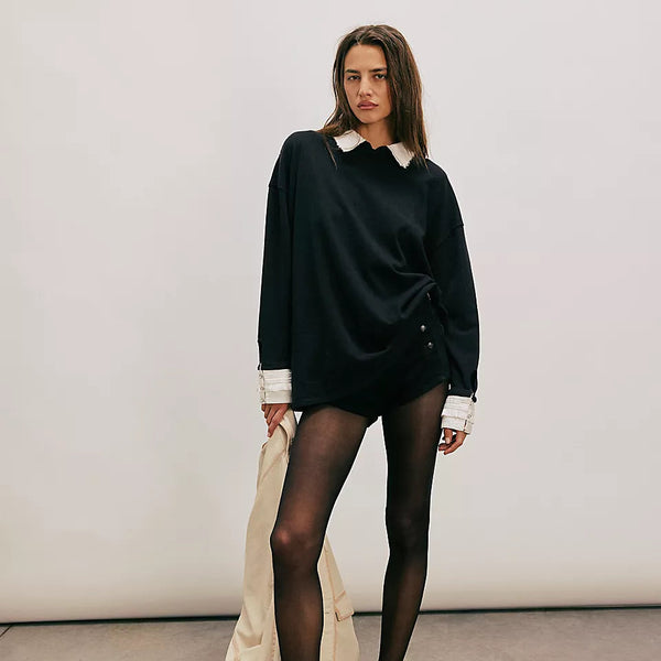 Woman wearing a black outfit with white accents against a plain background