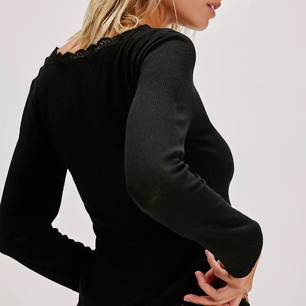 Woman wearing a black long-sleeve top with lace trim on a plain background