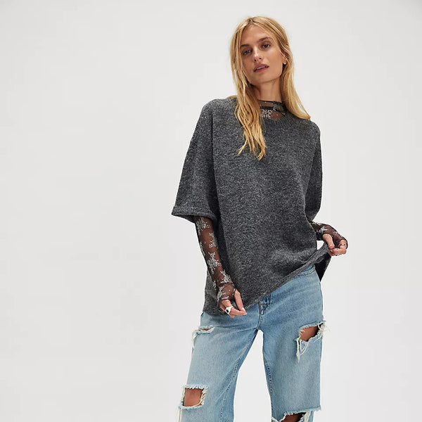 Person wearing a dark gray oversized sweater and light blue jeans on a white background