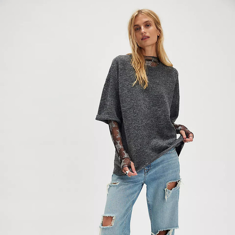 Person wearing a dark gray oversized sweater and light blue jeans on a white background