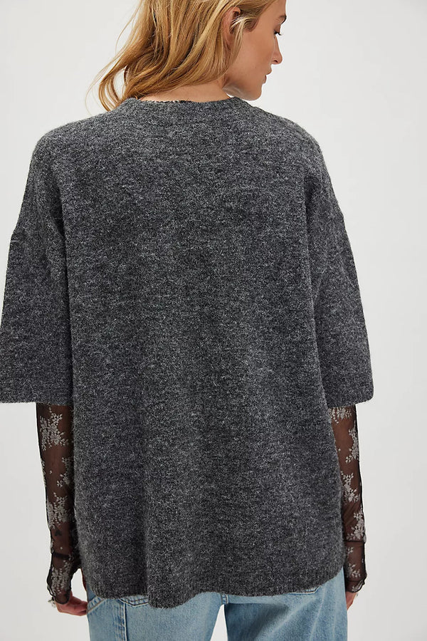 Person wearing a dark gray oversized sweater on a white background