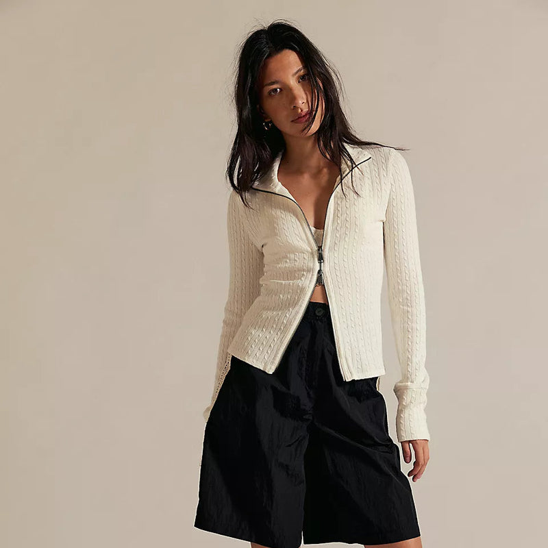 Woman wearing a white jacket, black shorts, and black shoes on a beige background