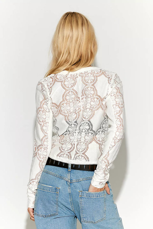 Person wearing a white lace top and blue jeans on a plain background