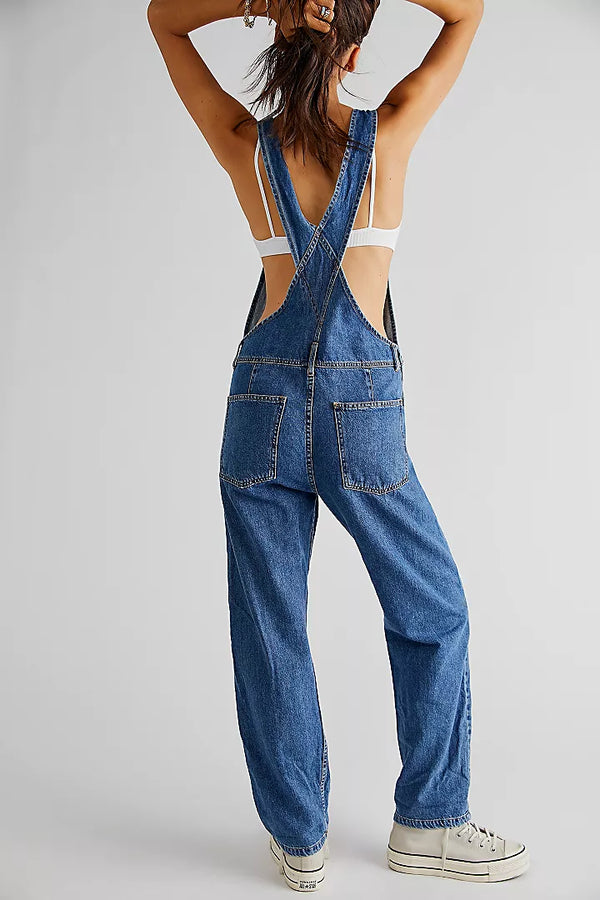 back view of the model wearing the ziggy denim overalls. shows the back patch pockets. also shows the slouchy fit, the adjustable straps and the tapered legs. 