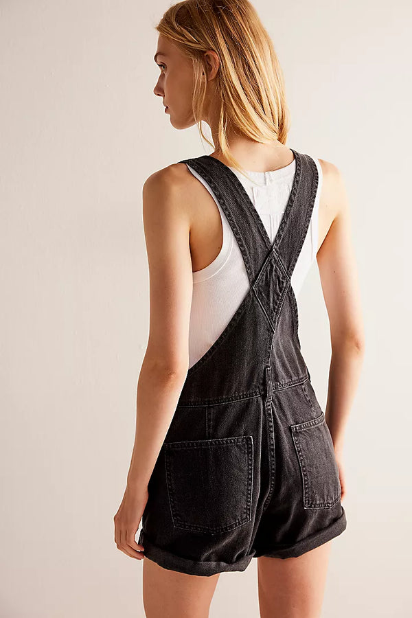 back view of the model wearing the ziggy shortalls. shows the back patch pockets. also shows the adjustable straps, the rolled cuffed hems and the relaxed fit. 