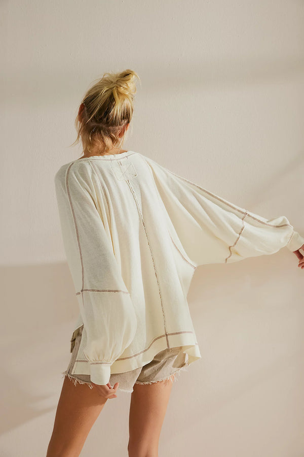back view of the model wearing the wish i knew tee. shows the  exaggerated sleeves and the exposed seaming. 