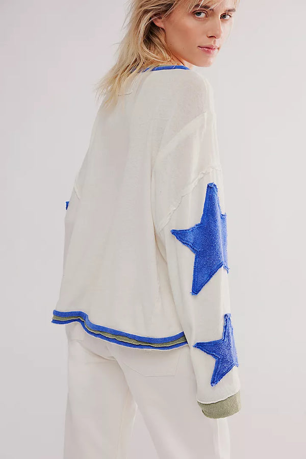 back view of the model wearing the youre a star tee. shows the raw hem. also shows the raised seaming, the oversized stars on the sleeves and the the dropped shoulders sleeves. 