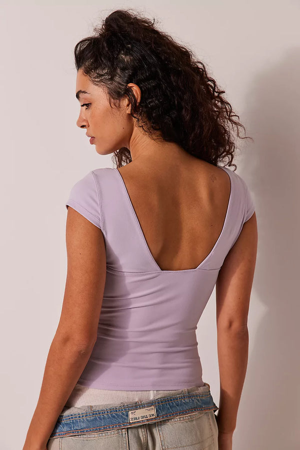 back view of the model wearing the duo corset cami. shows the lavender color. also shows the deep back neckline, the cap sleeves and the slim fit. 