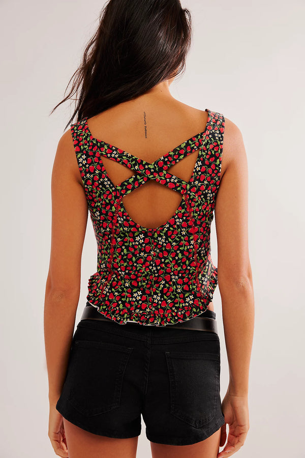 back view of the model wearing the melanie tank. shows the cute strawberry print. also shows the criss cross back, the rounded bottom hem & ruffle on the bottom. 