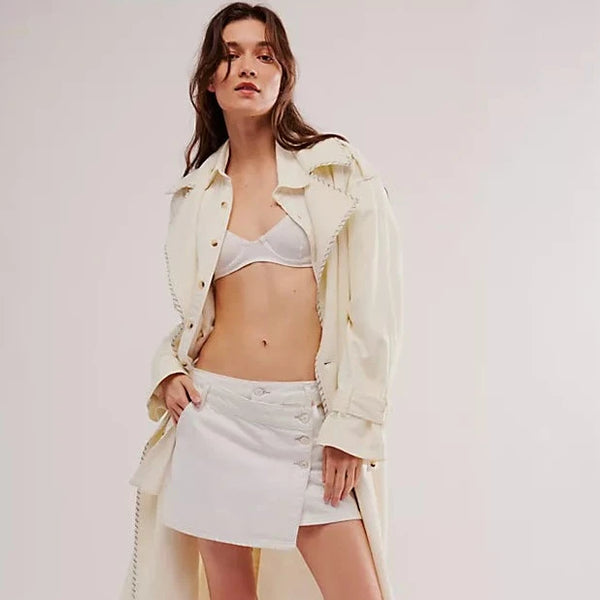 front view of the model wearing the wynne denim skirt. shows the side button closure. also shows the asymmetrical design, the mid rise and the belt loops. 