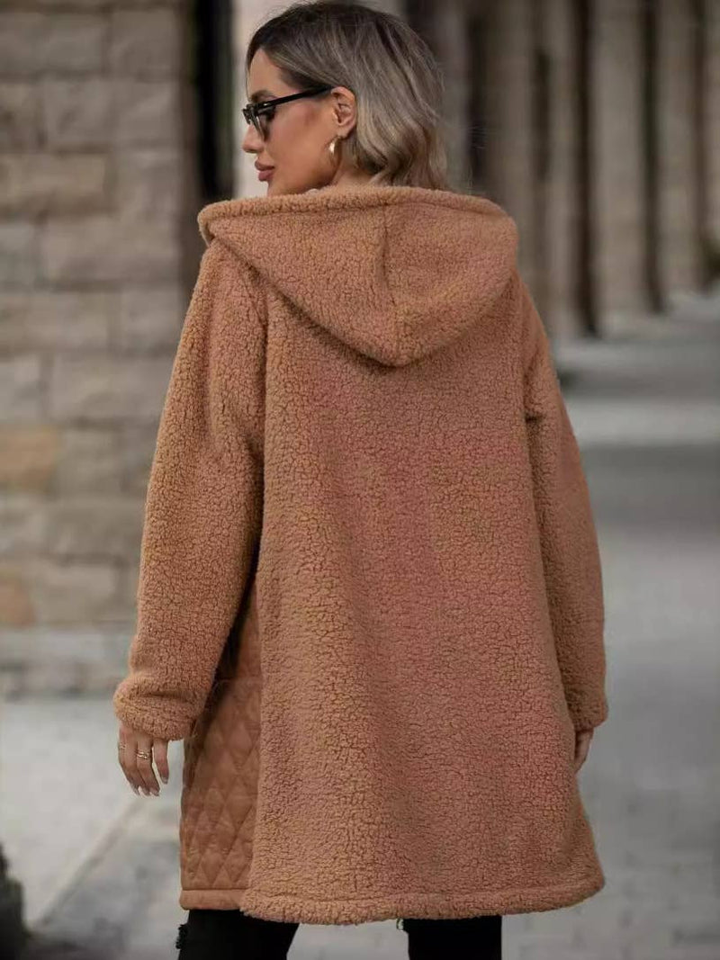 Person wearing a brown teddy coat with a hood in an urban setting.