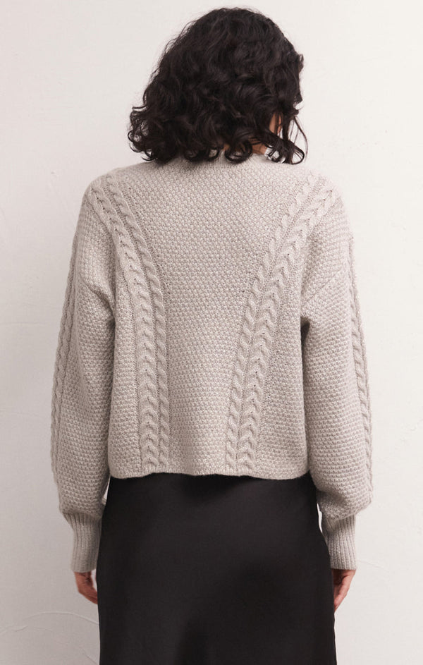 the back view of the eternal sweater in the color dove. shows the drop shoulders. also shows the cable knit detailing, the blouson sleeves and the ribbed detail on the cuffs.