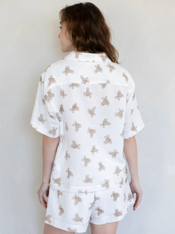 Person wearing a white pajama set with a teddy bear pattern against a plain background
