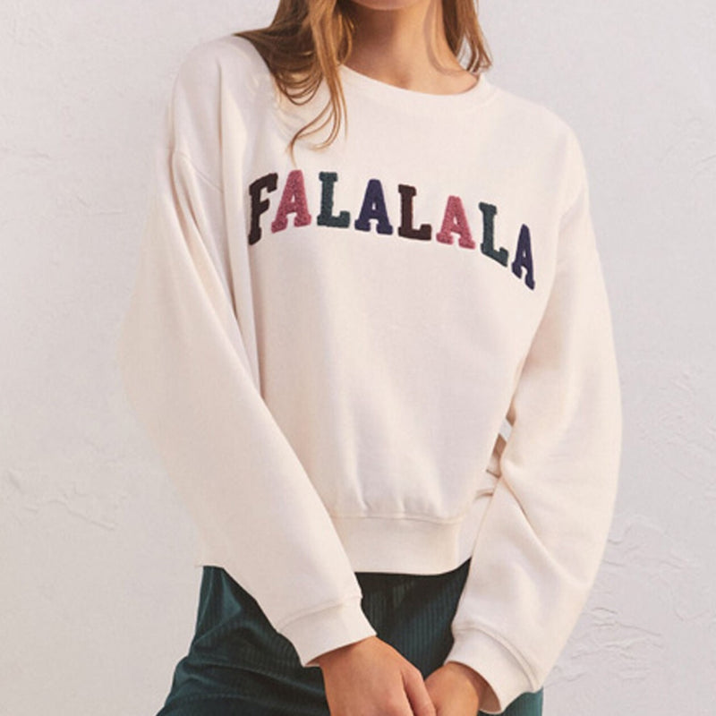 Front view of model wearing top. Shows the FALALALA multicolor chenille lettering on front. Also shows the crew neckline, the relaxed fit and the bone color.