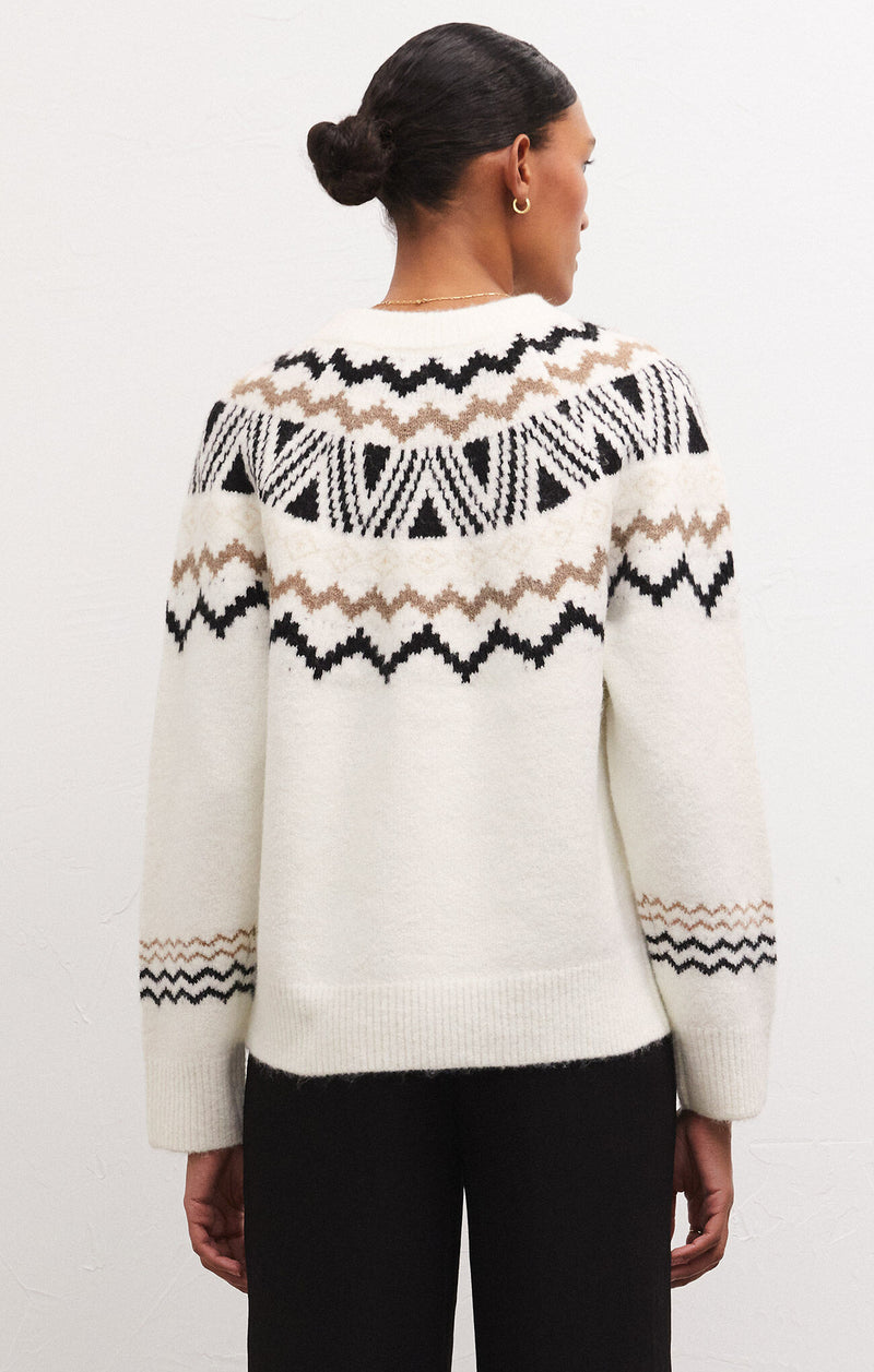 Back view of model wearing sweater. Shows the ribbing on the neck, cuffs and bottom hem. Also shows the relaxed fit, the beautiful fair isle print with browns and blacks and main color of sweater is sandstone. 