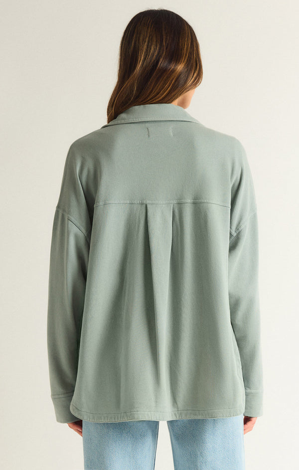 back view of the model wearing the all day knit jacket. shows the bottom curved hem. also shows the pleating on the back, the collar, the oversized fit and the love sleeves. 