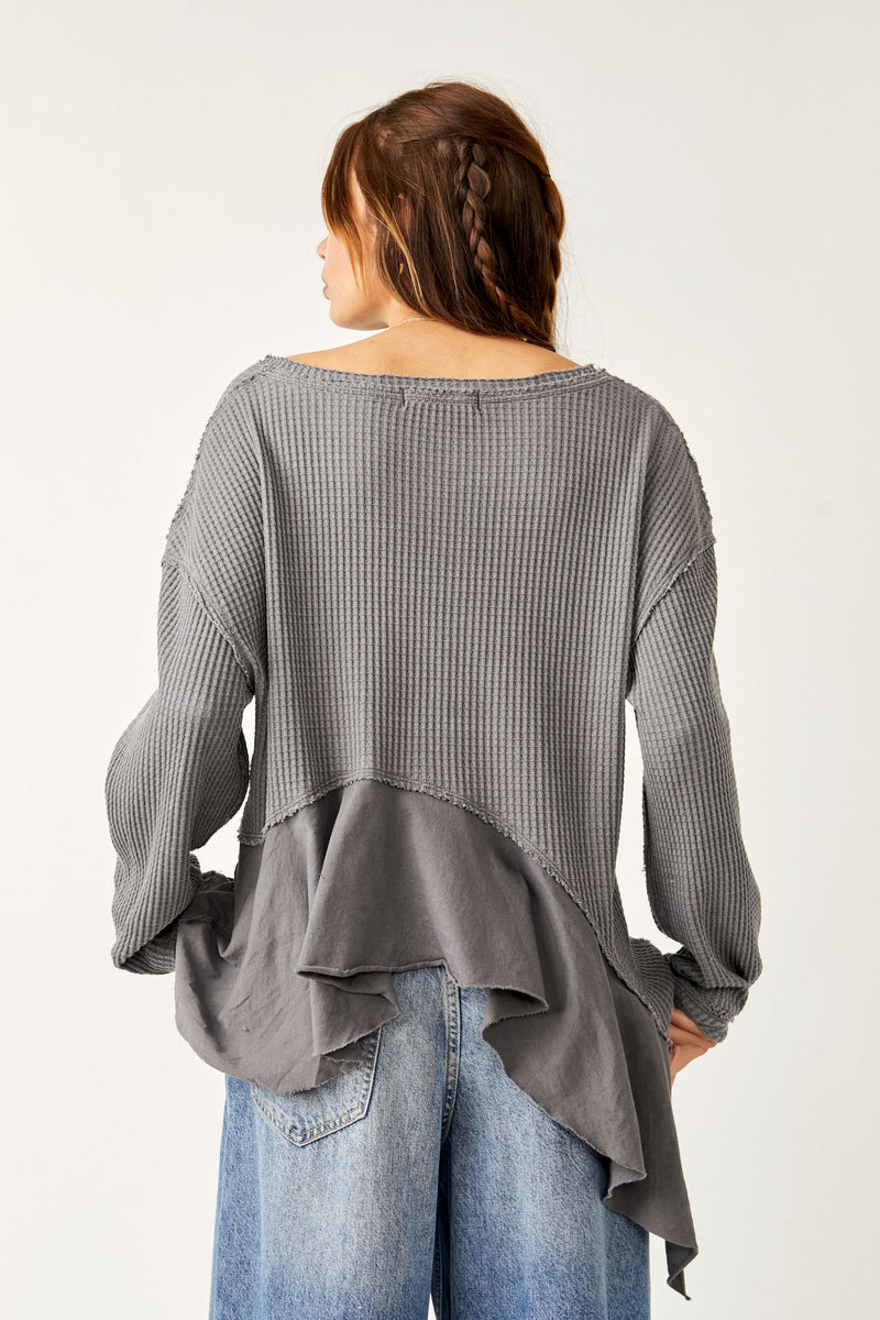 Back view of model wearing the vada thermal. Shows the asymmetrical bottom hem. Also shows the scoop neckline and the drop shoulder hem. 