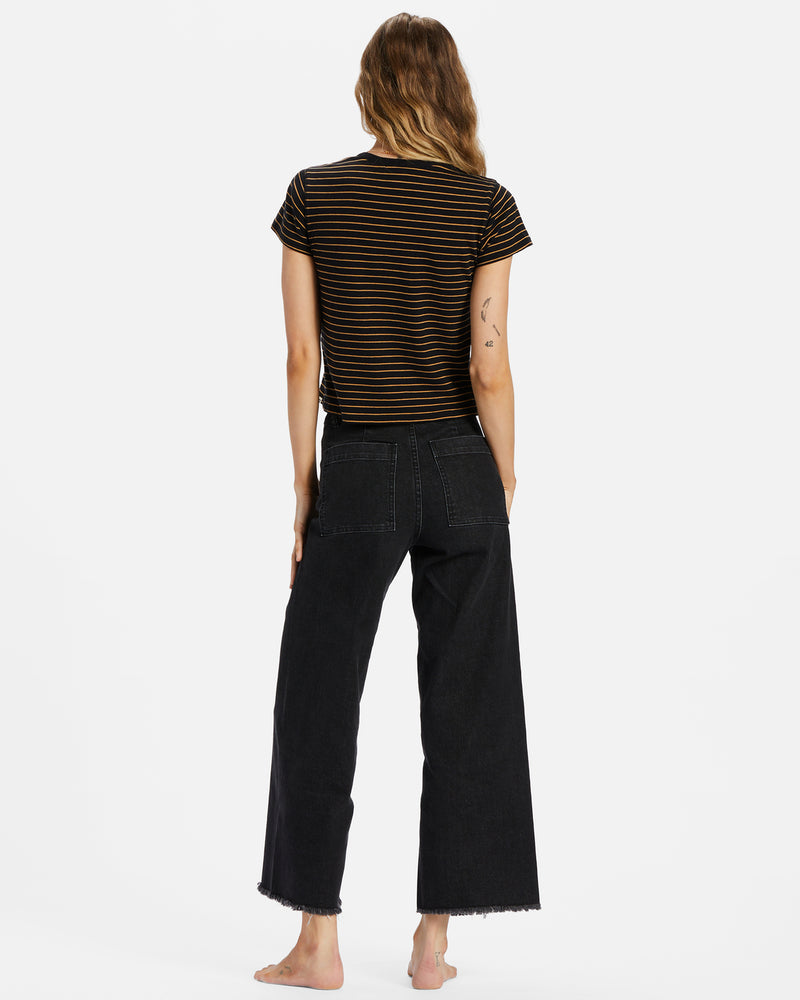 Back view of model wearing pants. Shows the back square pockets. Also shows the wide leg and raw hem in this beautiful black color. 