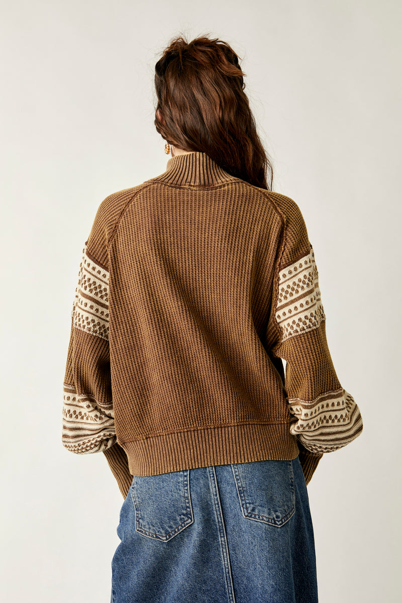 back view of model wearing the get cozy swit in hot fudge. shows the cream detail on the sleeves. also shows the tight cuffs and puff sleeves, the ribbed hems and the slouchy fit. 