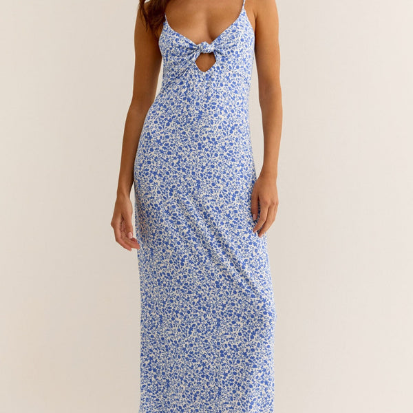 front view of the carita cocos floral midi dress. shows the front knot detail. also shows the spaghetti straps, the low scoop neckline and the midi length. 